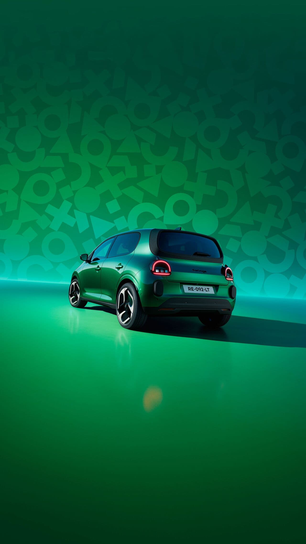 Renault Twingo in Vert Absolu von hinten vor einer Symbol-Wand